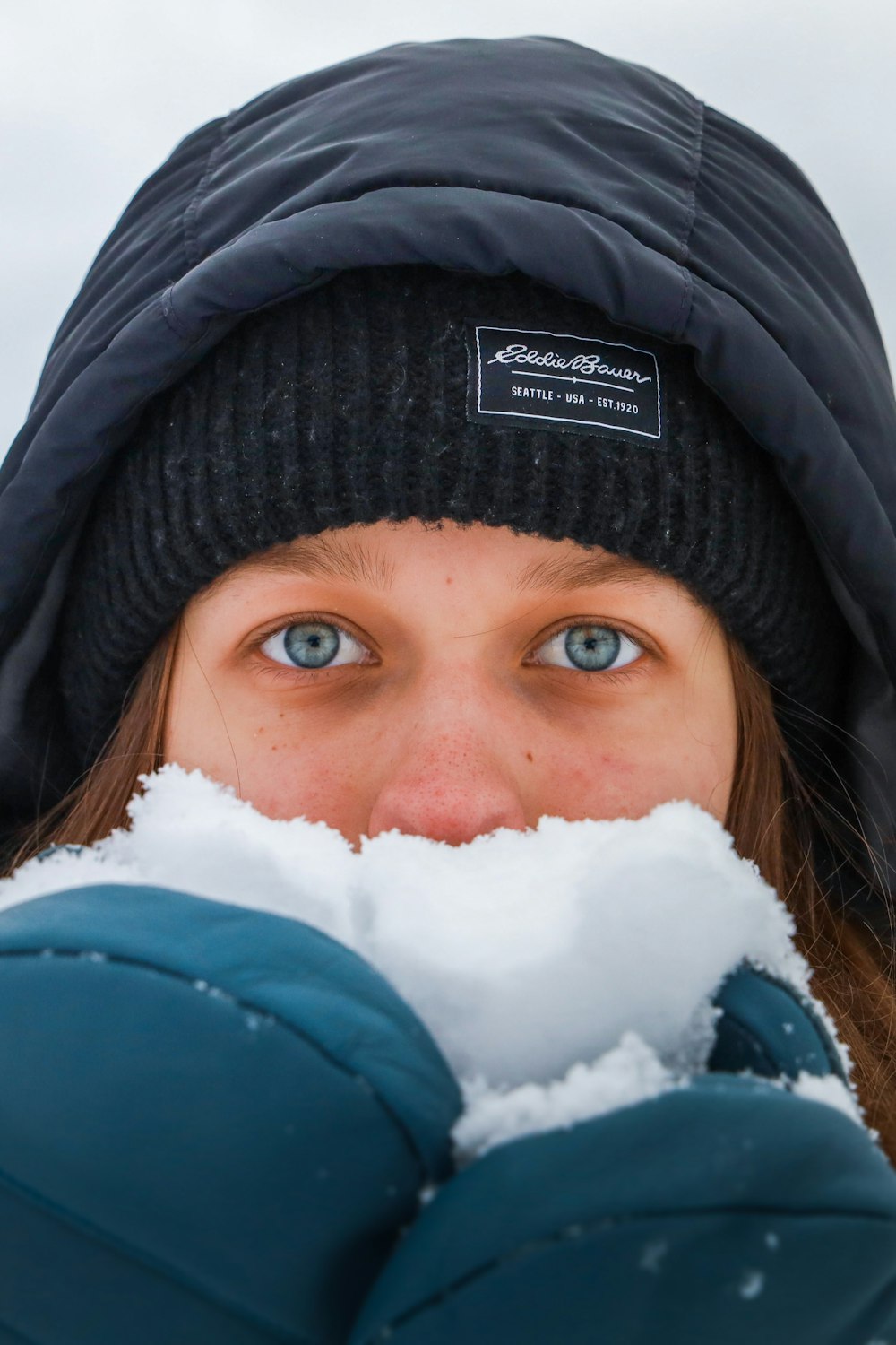 Une femme aux yeux bleus se couvre le visage de neige