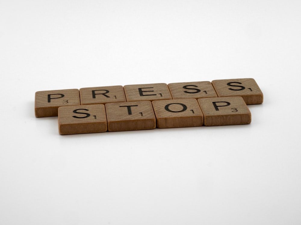 a set of wooden blocks spelling press and stop