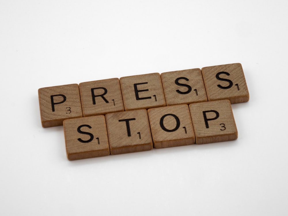 the word press stop spelled with wooden blocks