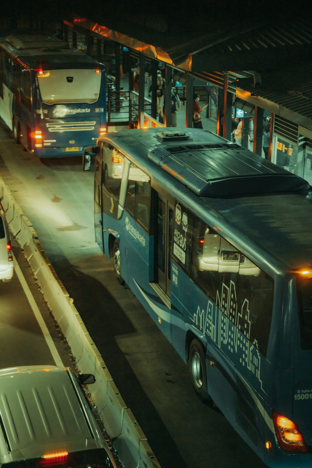 a blue bus driving down a street at night