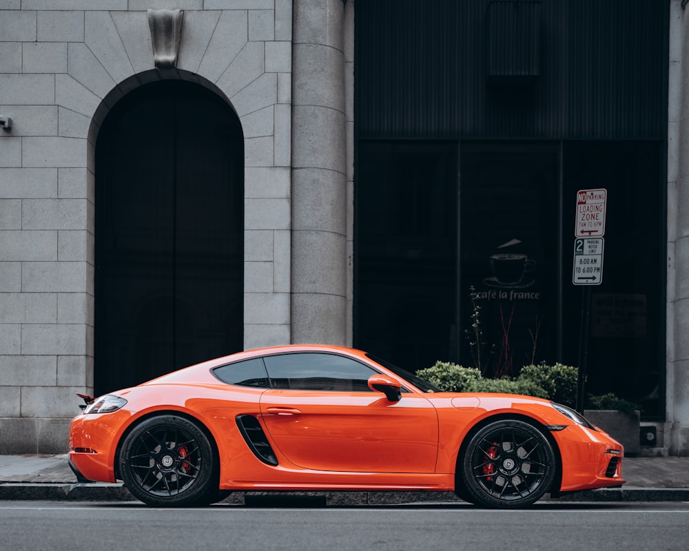 an orange sports car parked on the side of the road