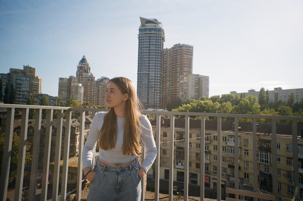 a woman standing on a balcony in front of a city