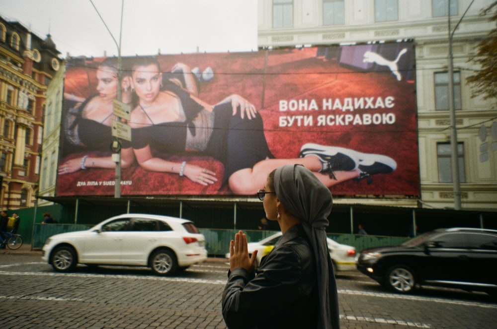 a woman is standing in front of a billboard