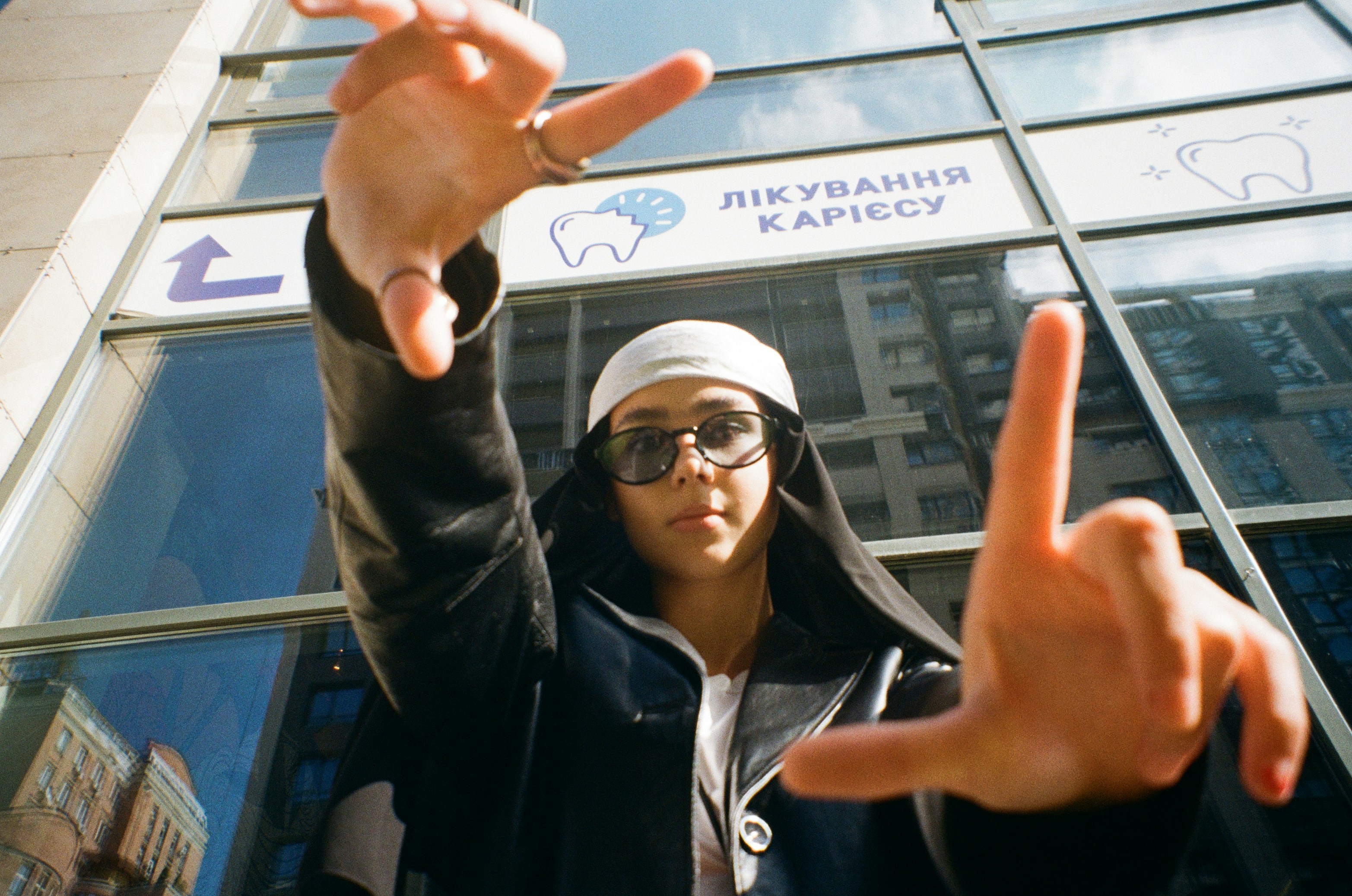 a man in a black jacket and a white hat making a peace sign