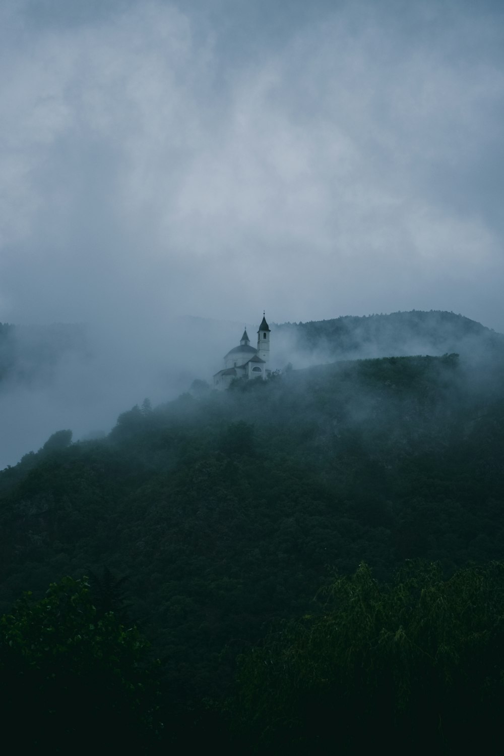 uma igreja no topo de uma colina coberta de nevoeiro