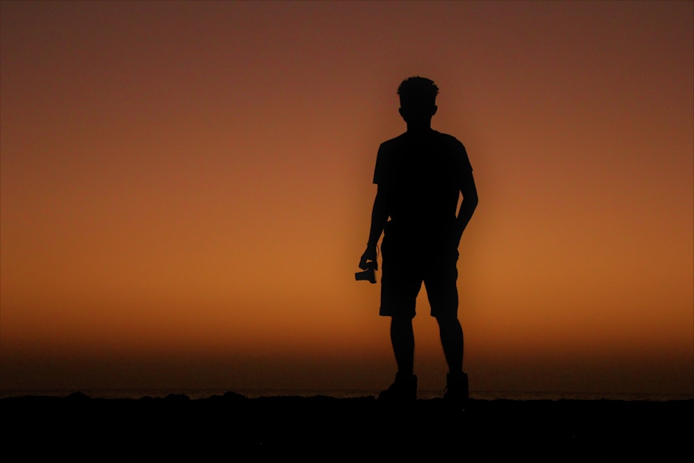 a silhouette of a man standing in front of a sunset