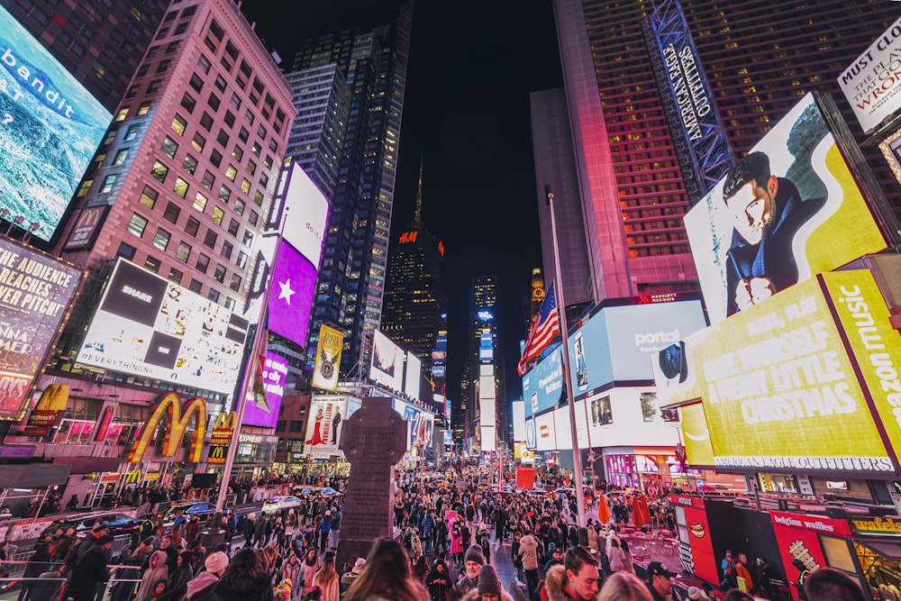 a crowd of people walking around a city at night