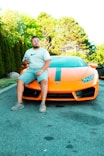 a man sitting on top of an orange sports car