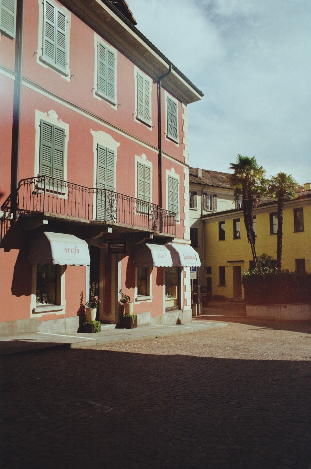 a pink building with white shutters and balconies