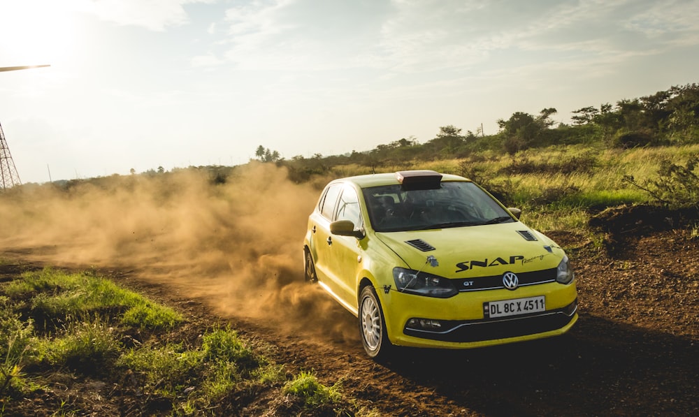 a yellow car driving down a dirt road