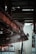 A complex metal structure with interconnected pipes and beams, part of an industrial or mechanical setup, is visible. Steam or smoke is emanating from the equipment, which is colored dark brown and black.