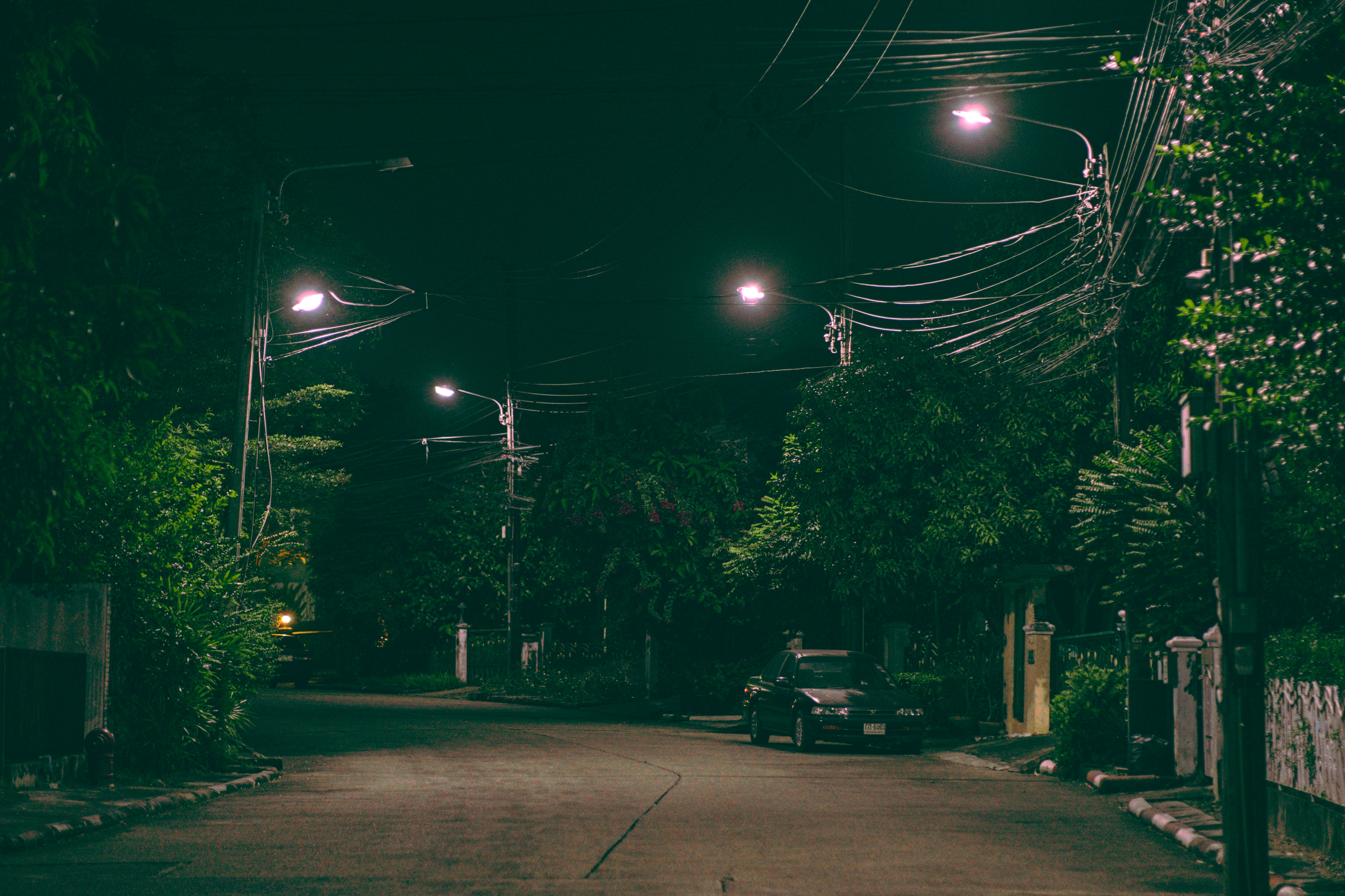 a street at night with a car parked on the side of the road