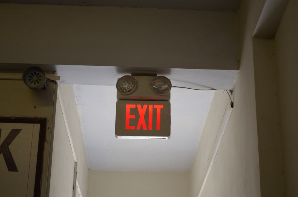 a red exit sign hanging from the ceiling of a hallway