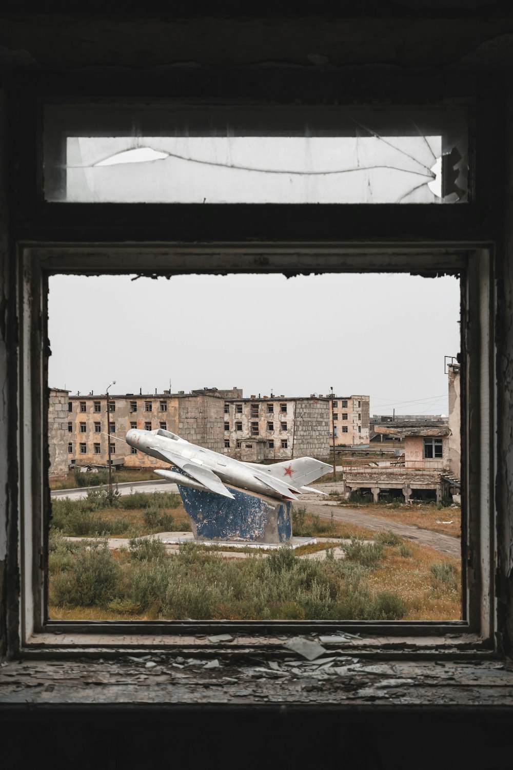 a plane sitting on top of a field next to a window