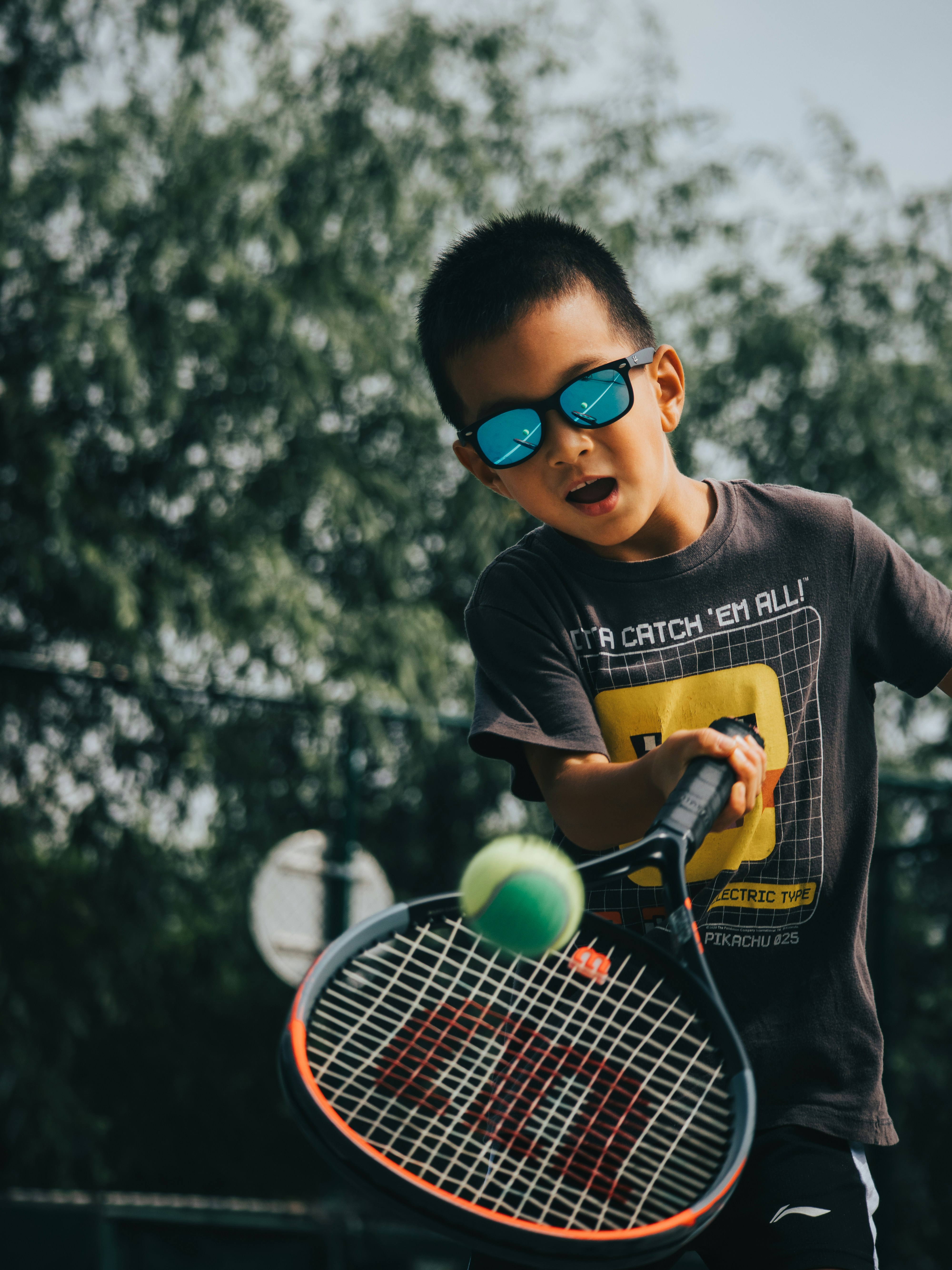 a young boy holding a tennis racquet on top of a tennis court