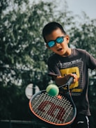 a young boy holding a tennis racquet on top of a tennis court