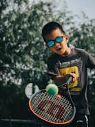 a young boy holding a tennis racquet on top of a tennis court