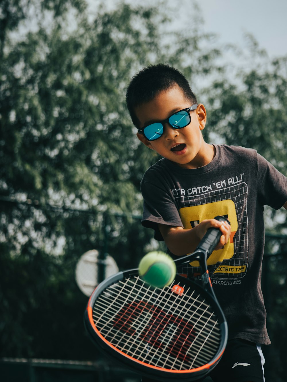 a young boy holding a tennis racquet on top of a tennis court