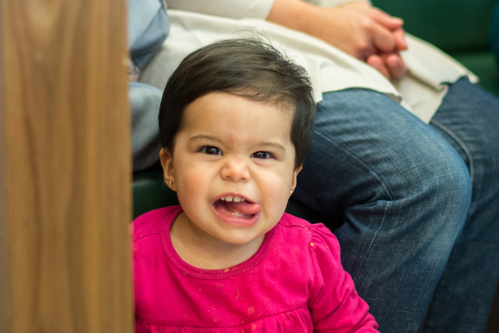 Une petite fille assise sur un canapé, la bouche ouverte