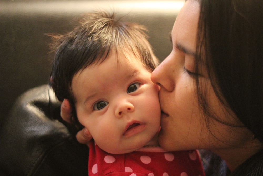 a woman kissing a baby on the cheek