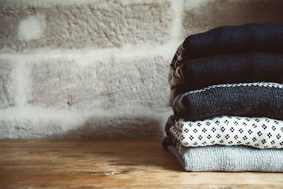 Flat lay of folded winter jerseys in various colors on a rustic surface.