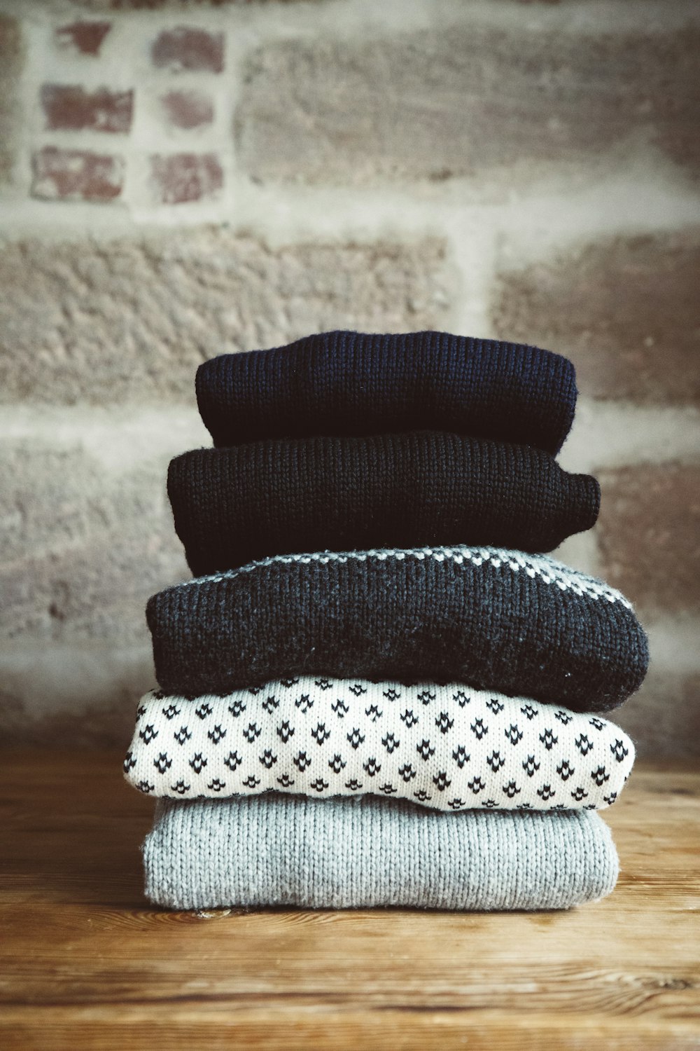a stack of sweaters sitting on top of a wooden table