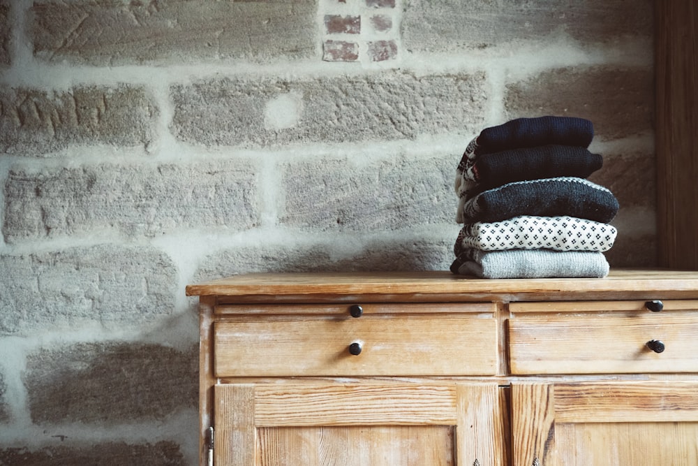 a stack of folded towels sitting on top of a wooden dresser