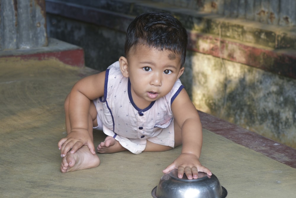 a small child laying on the ground next to a metal object