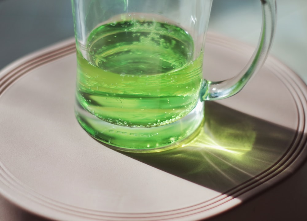 흰색 접시 위에 앉아 녹색 액체 한 잔