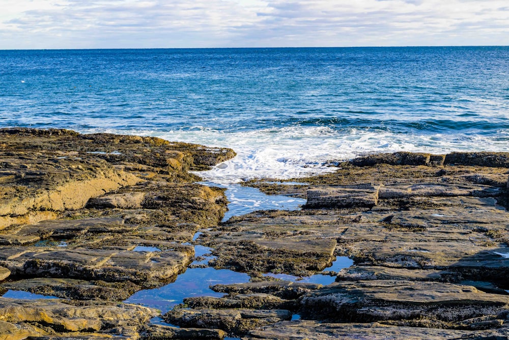 a rocky shore with a body of water in the distance