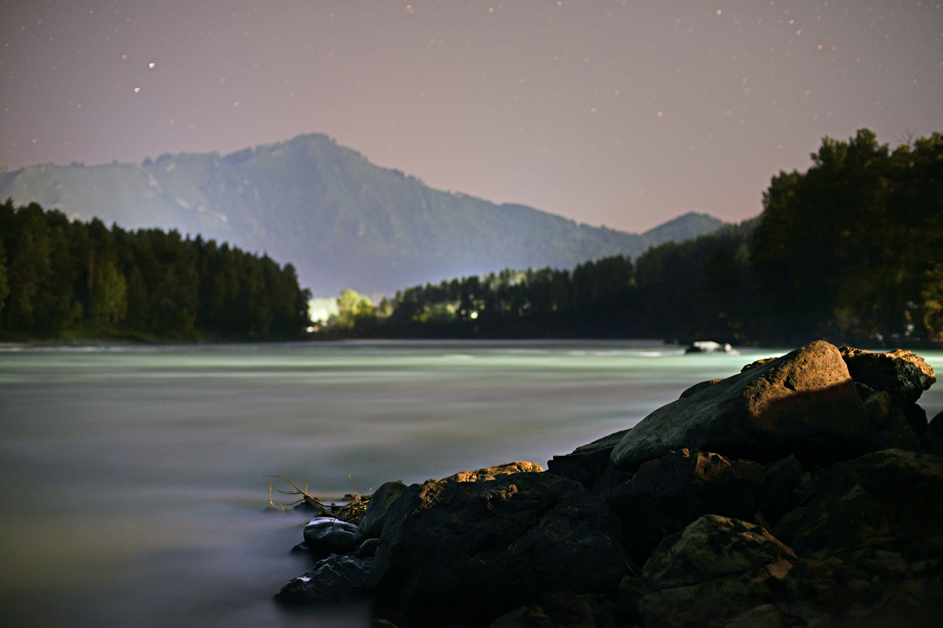 a night time view of a lake with mountains in the background