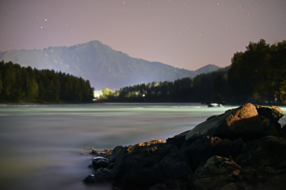 a night time view of a lake with mountains in the background