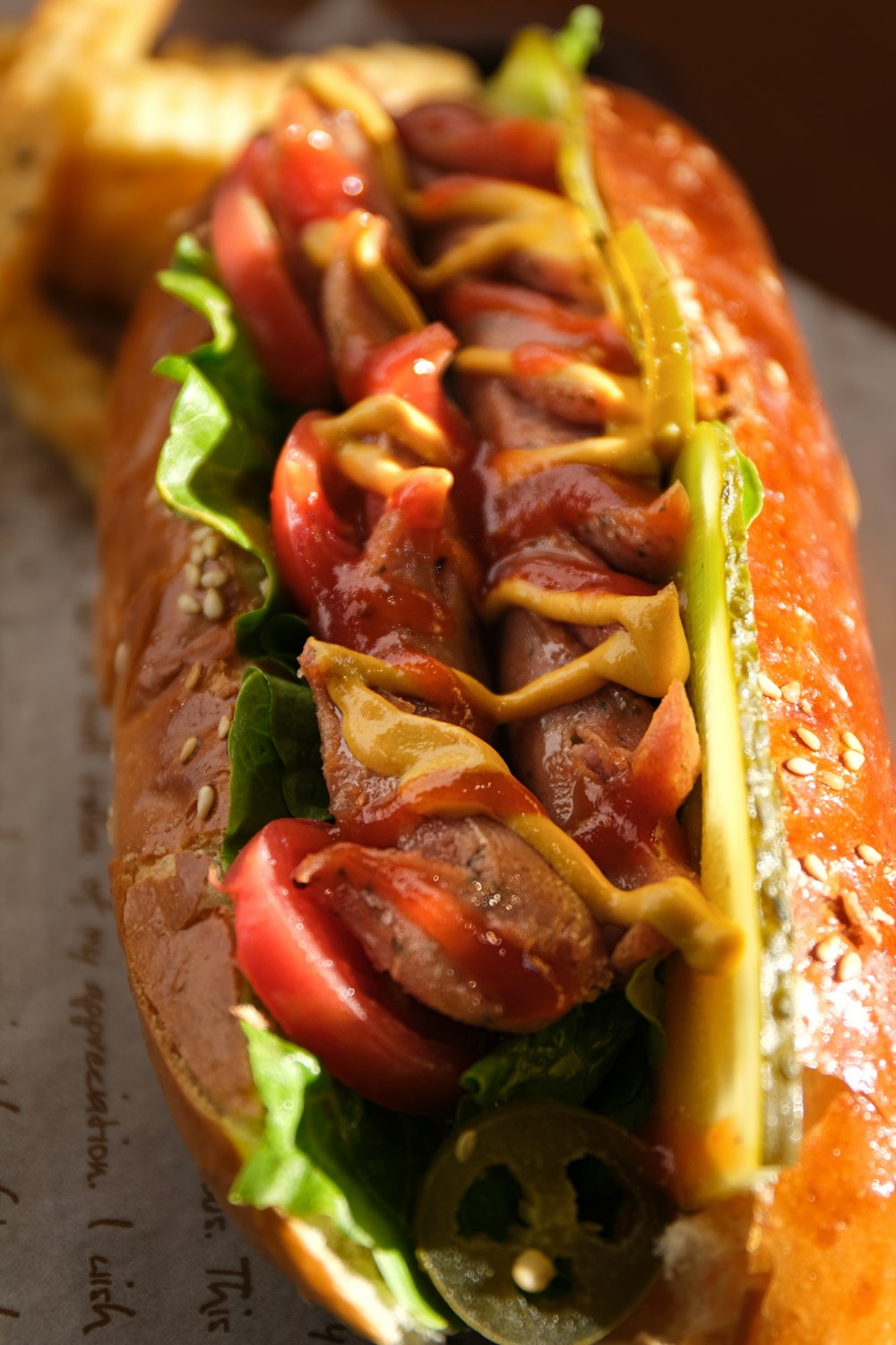 a hot dog with tomatoes, lettuce, and mustard