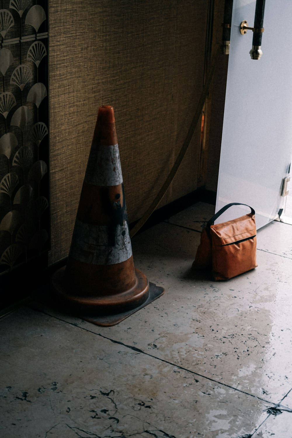 a traffic cone sitting on the floor next to a bag