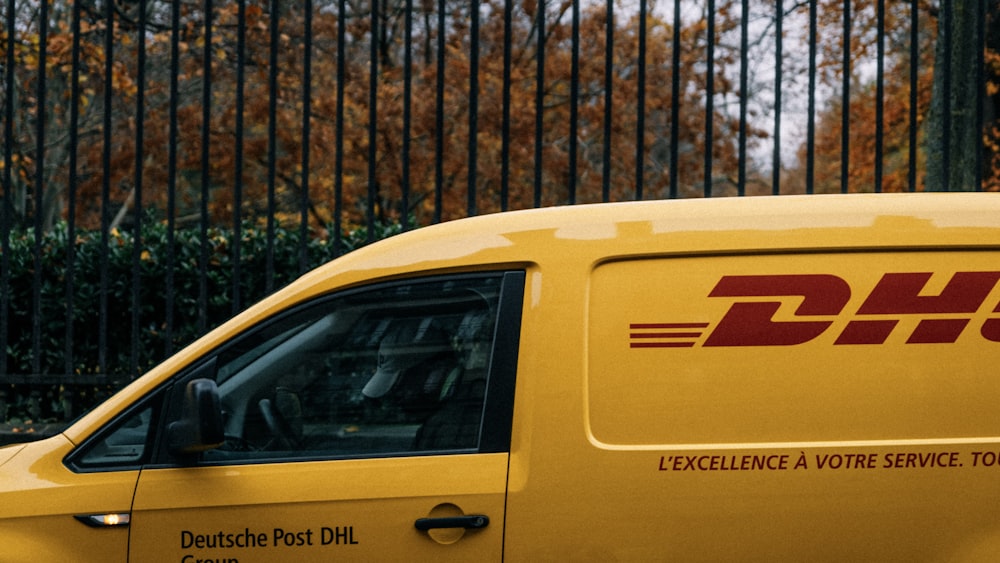 a dhl delivery truck parked in front of a fence