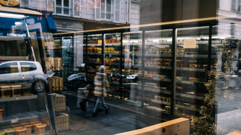 a person walking past a store front with a car in the window