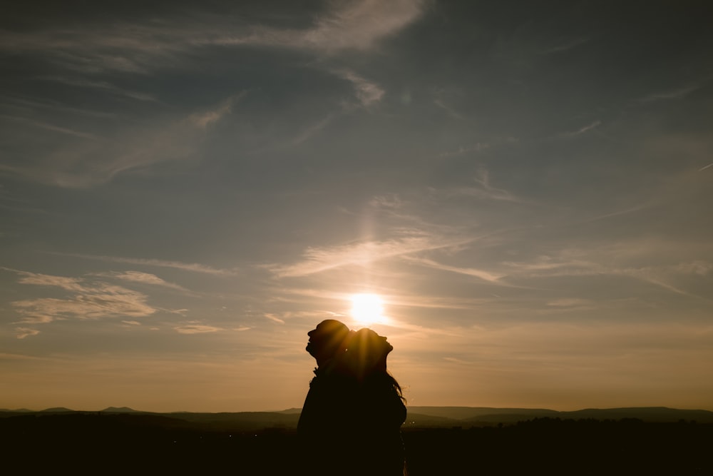 a silhouette of a person and a dog at sunset