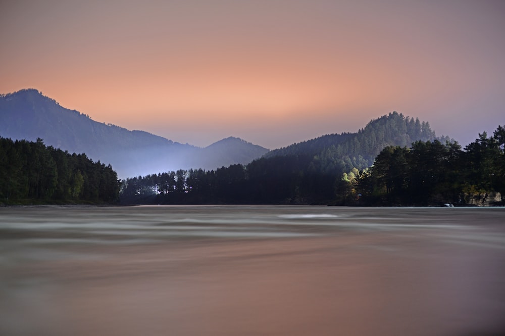 a body of water surrounded by trees and mountains