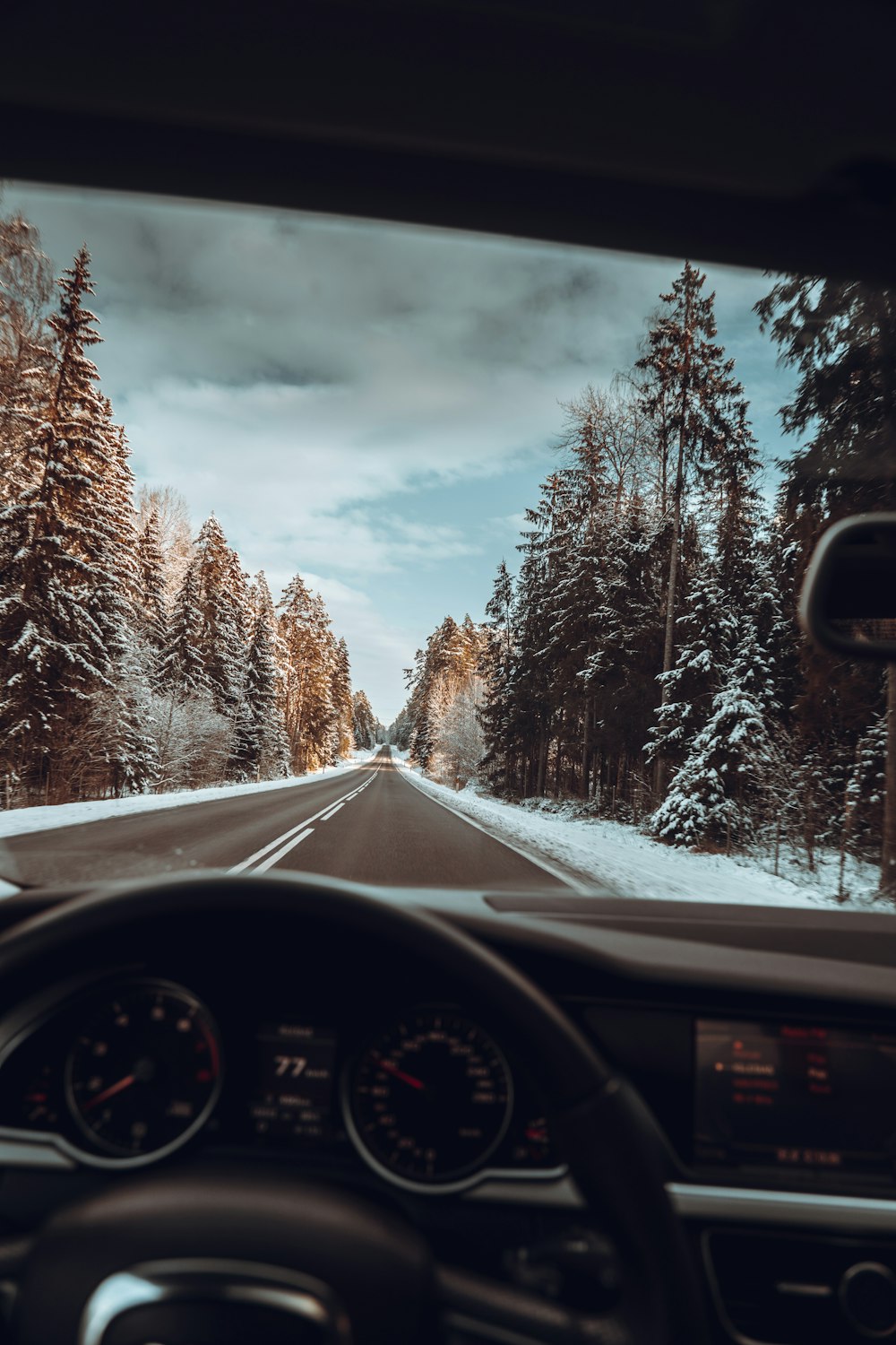 a car driving down a snowy road next to a forest