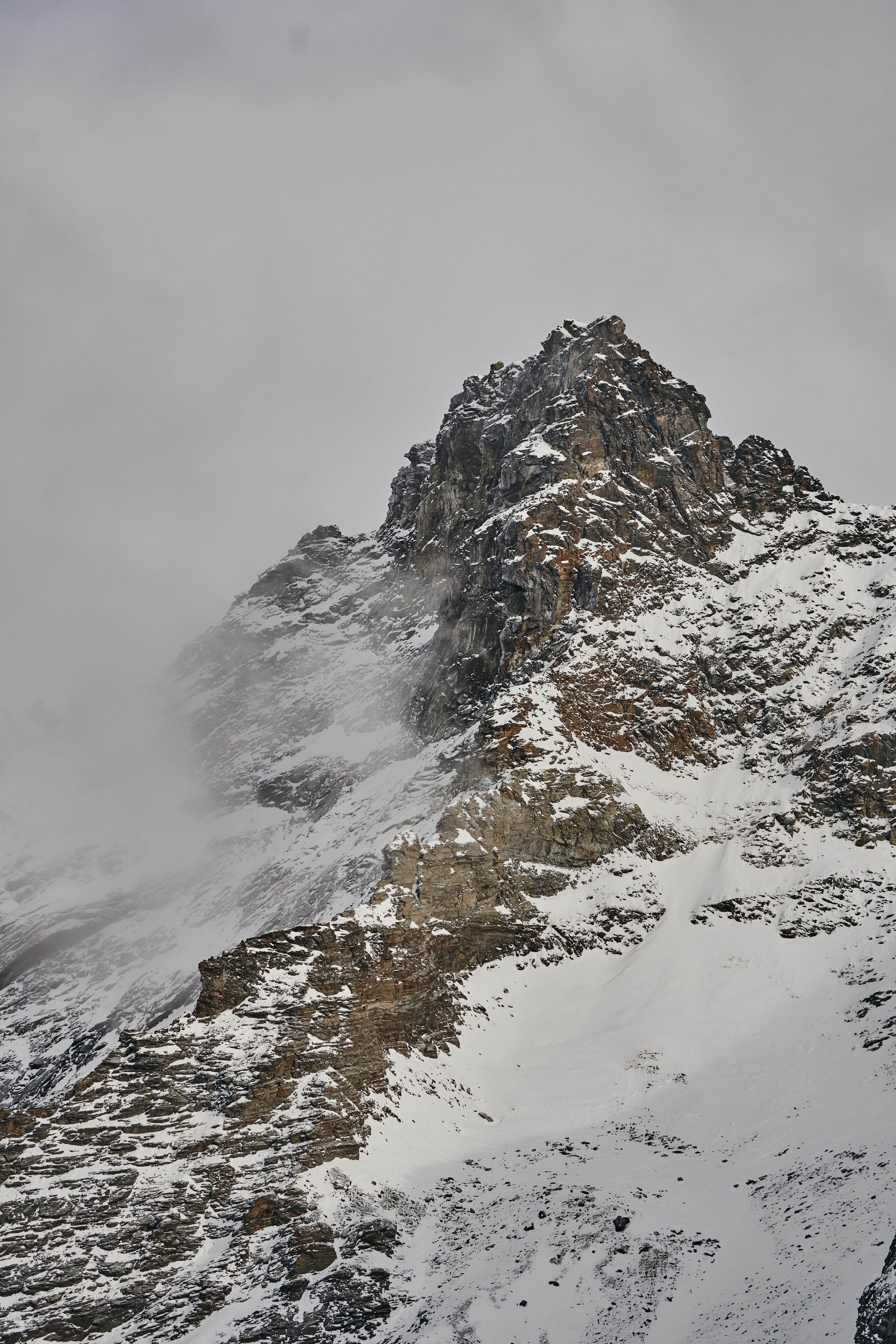 a mountain covered in snow and surrounded by clouds