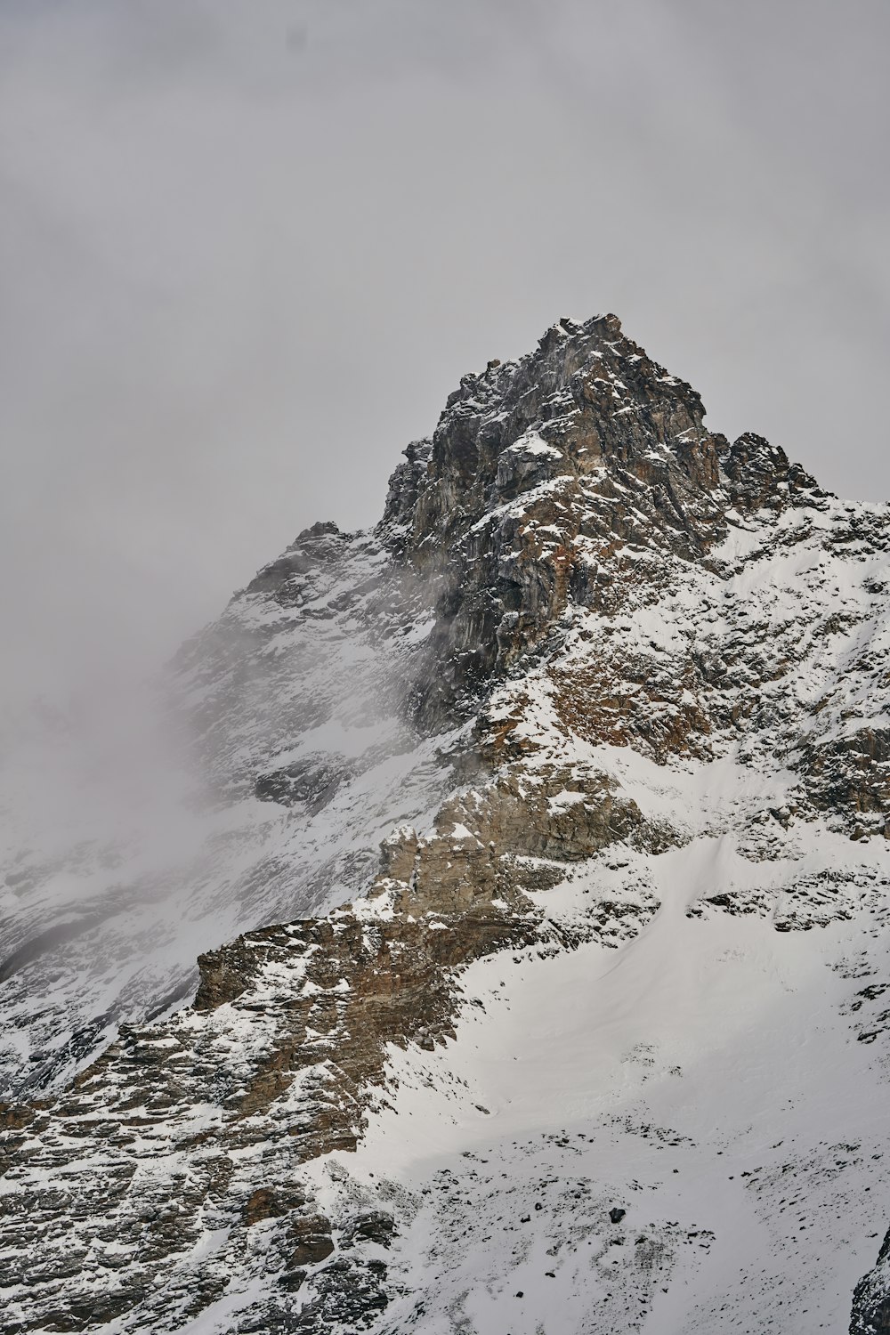 a mountain covered in snow and surrounded by clouds