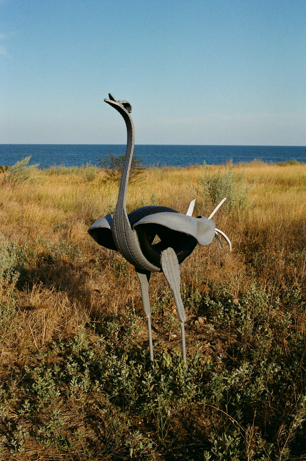 a statue of an ostrich standing in a field