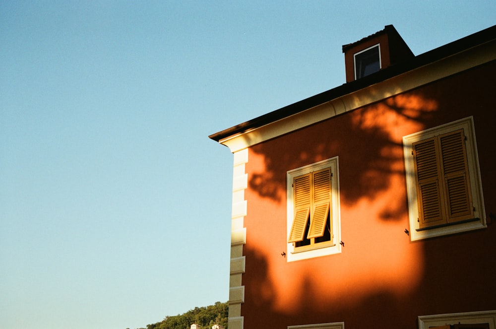 a red building with two windows and a clock