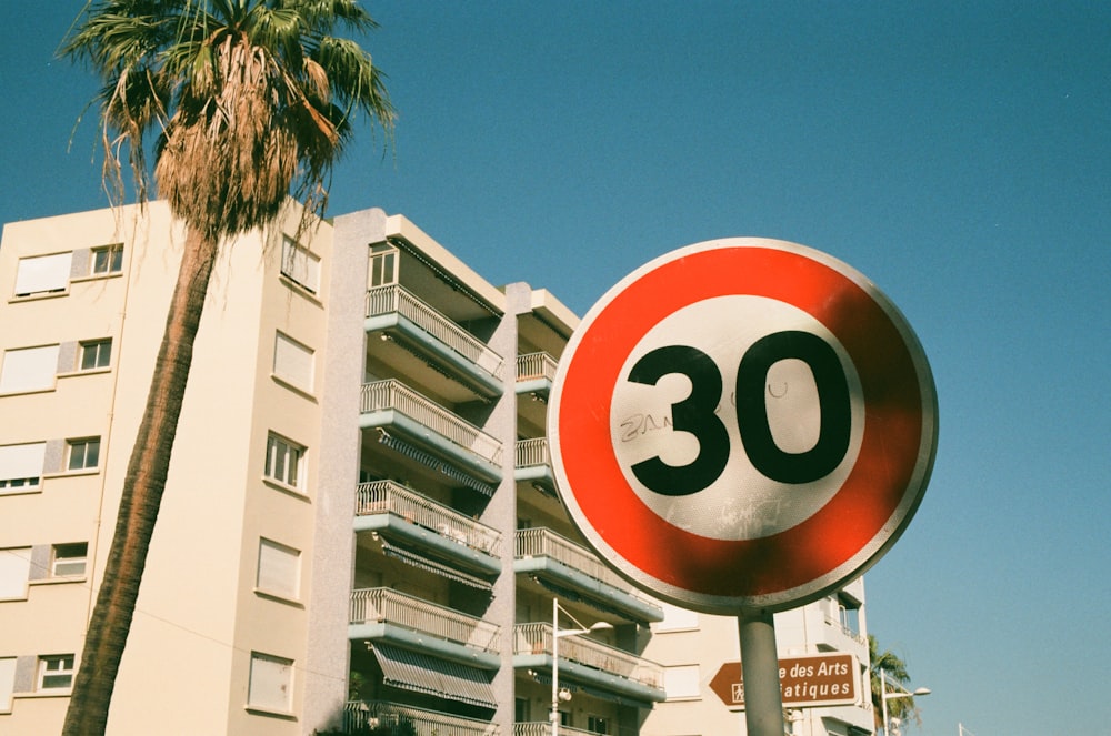 a red and white speed limit sign next to a tall building