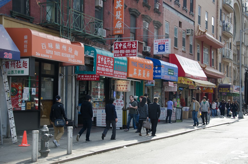 a group of people walking down a street next to tall buildings