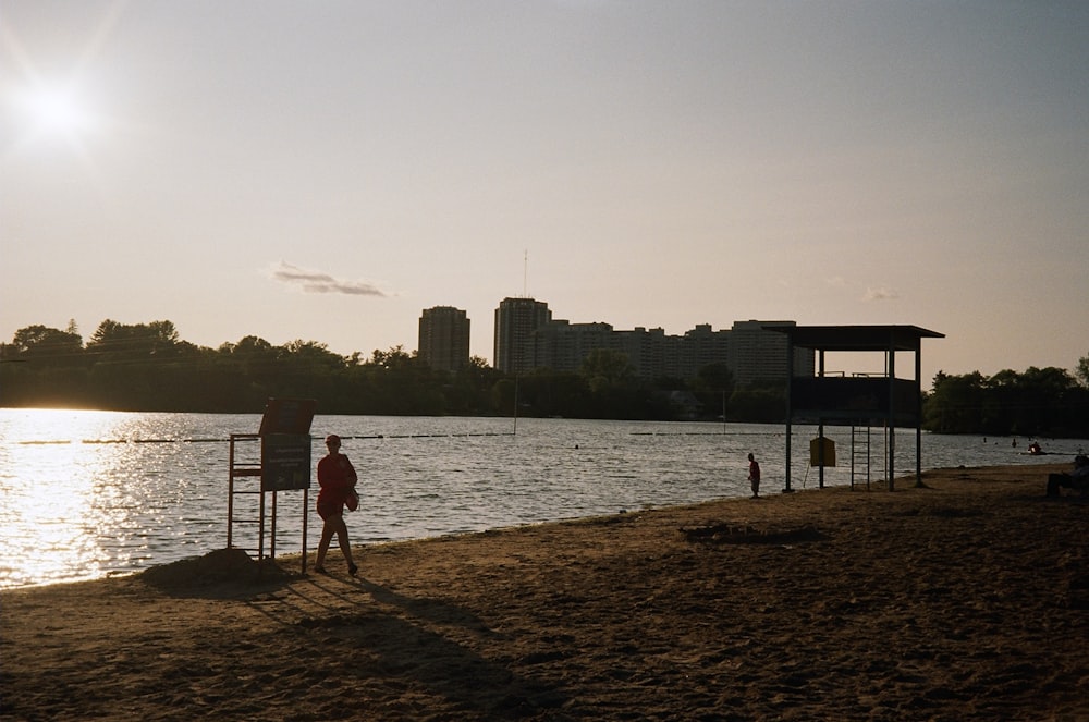 a couple of people standing on a beach next to a body of water