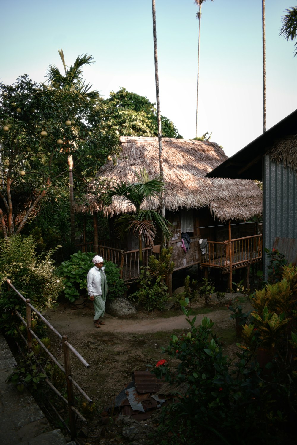 a man standing in front of a hut with a thatched roof