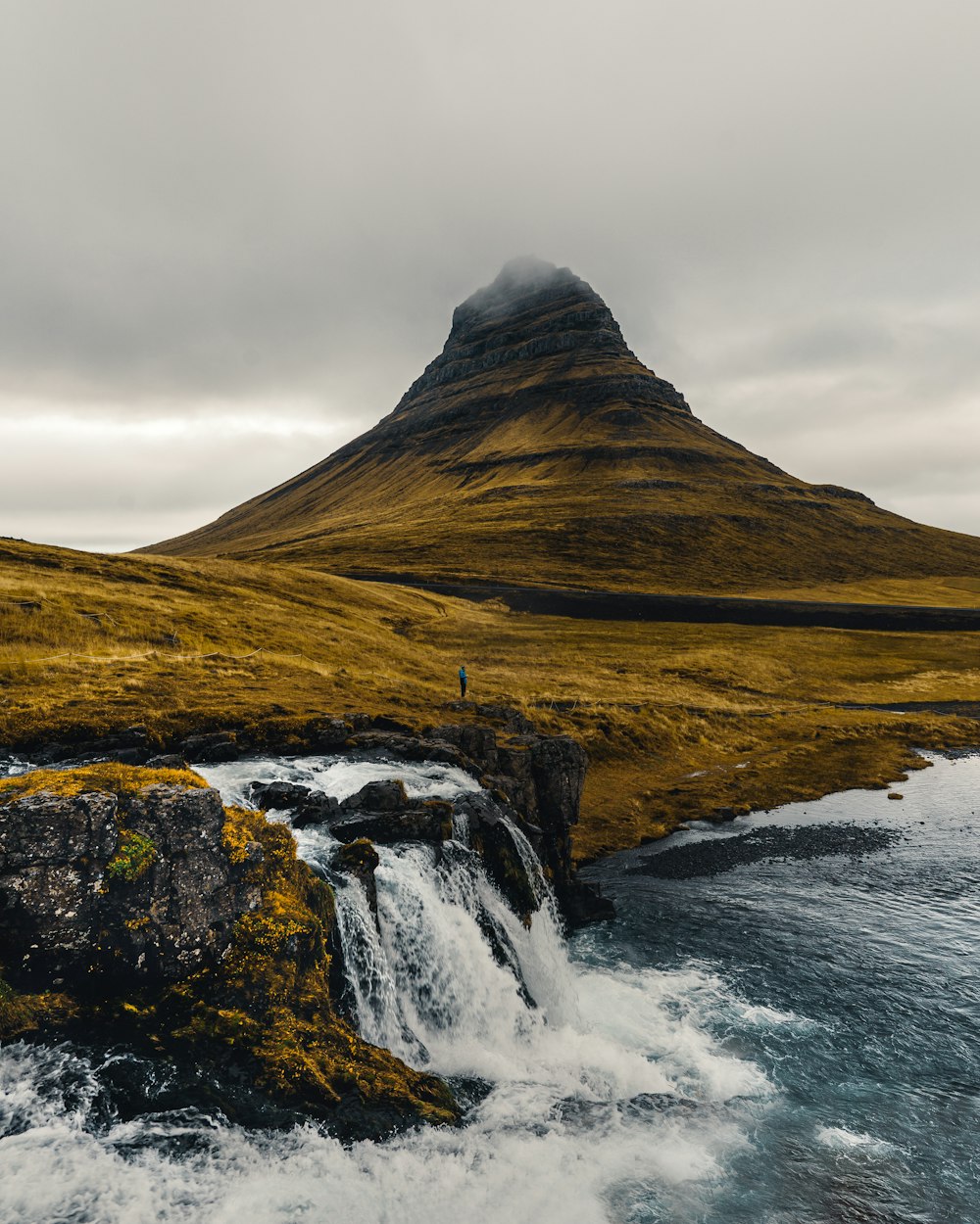 a man standing on top of a mountain next to a waterfall