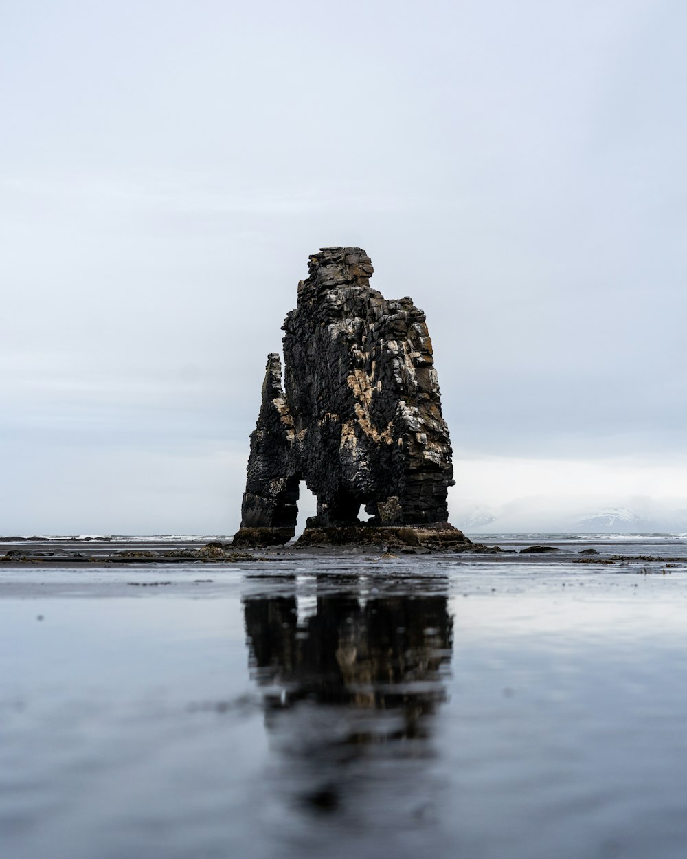 a rock sticking out of the water on a beach