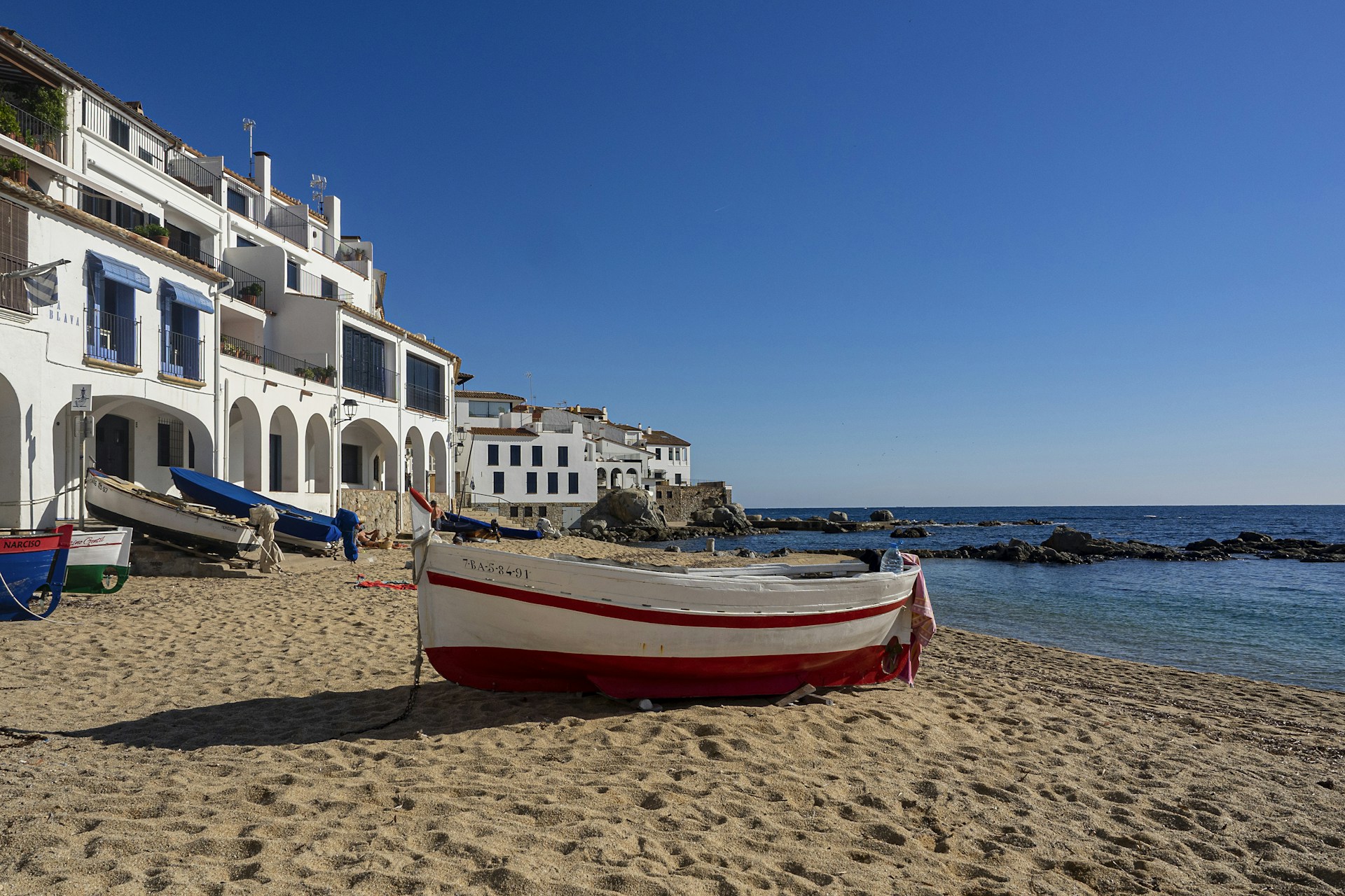 a red and white boat sitting on top of a sandy beach